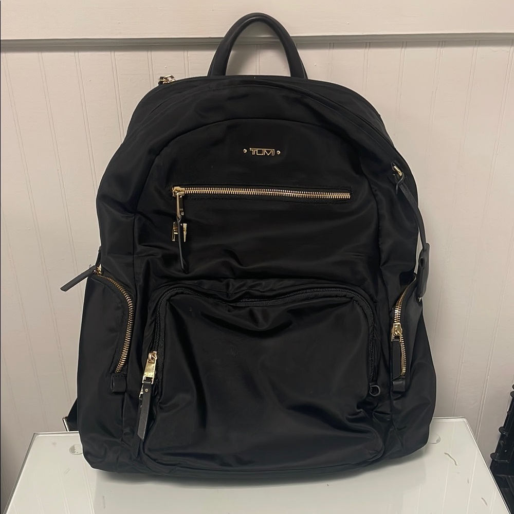 Tumi Black Backpack with Gold Zippers and Padded Straps